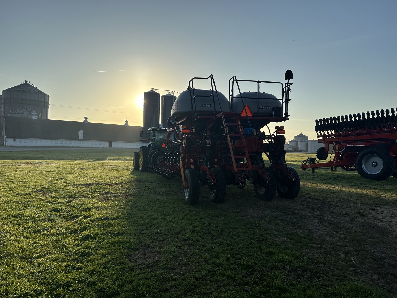 Planting equipment silhouetted by sunrise at the grain facility