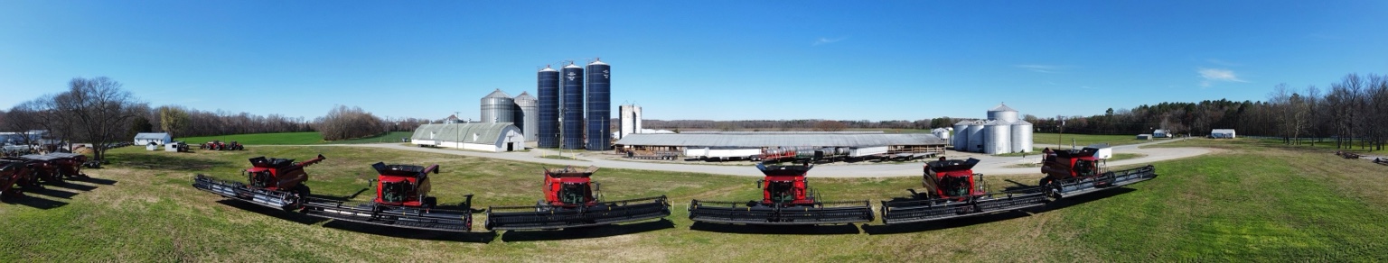 Panoramic lineup of combines in front of the grain facility